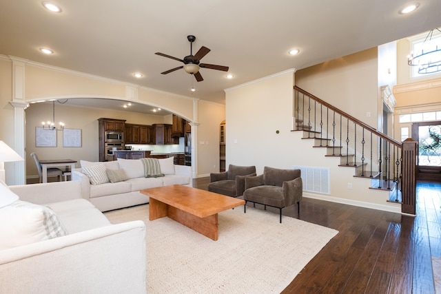 living room with visible vents, baseboards, dark wood finished floors, ceiling fan with notable chandelier, and arched walkways