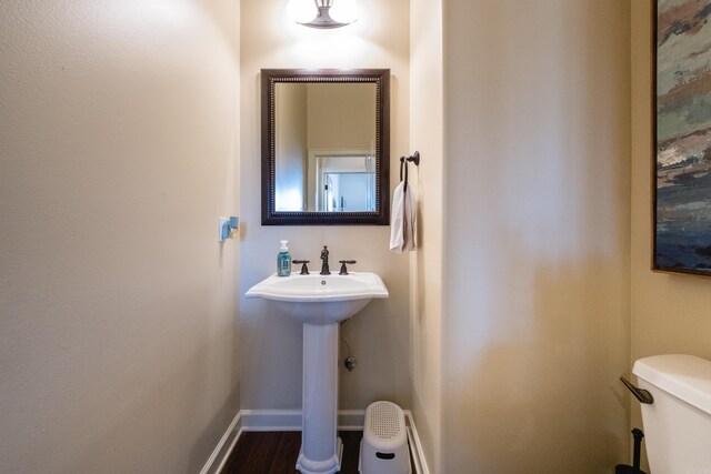 half bathroom with baseboards and toilet