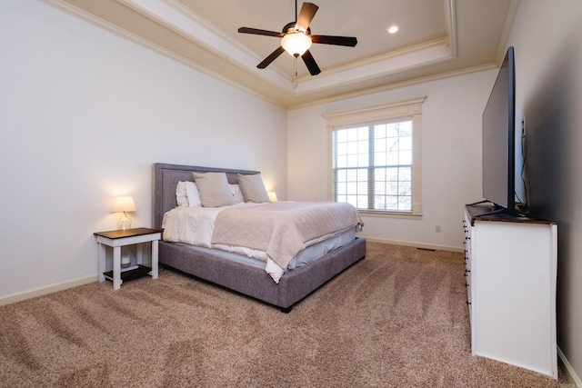 carpeted bedroom featuring a tray ceiling, recessed lighting, baseboards, and ornamental molding