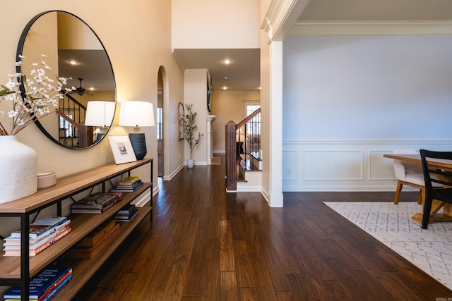 foyer featuring a wainscoted wall, stairs, wood-type flooring, crown molding, and a decorative wall