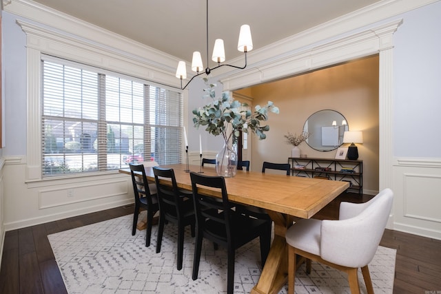 dining room with a wainscoted wall, a notable chandelier, dark wood-style flooring, and ornamental molding