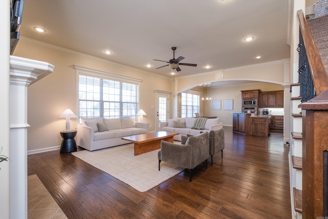 living area with arched walkways, dark wood-style floors, a ceiling fan, and crown molding