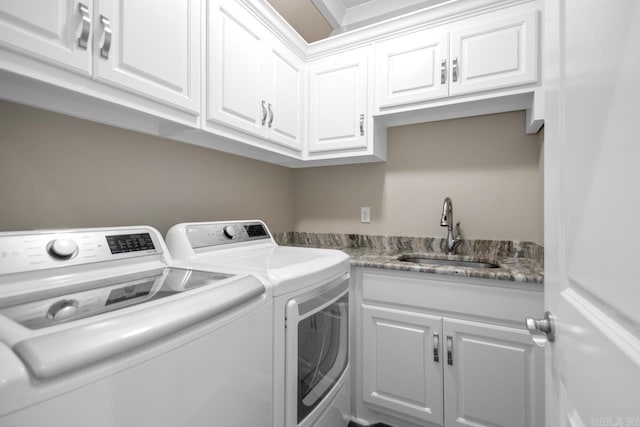 clothes washing area with a sink, cabinet space, and washer and clothes dryer