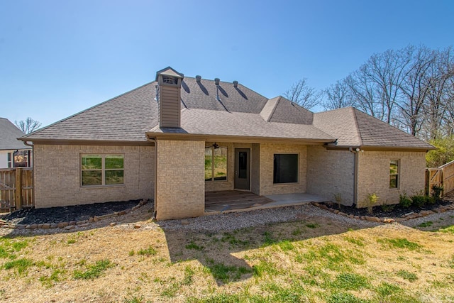 rear view of property with a patio area, brick siding, roof with shingles, and fence