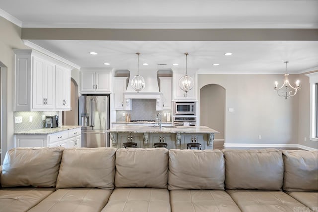 living room with crown molding, baseboards, recessed lighting, an inviting chandelier, and arched walkways