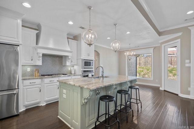 kitchen featuring backsplash, appliances with stainless steel finishes, an inviting chandelier, custom exhaust hood, and a sink