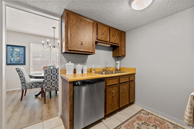 kitchen with brown cabinets, a sink, light countertops, dishwasher, and a chandelier