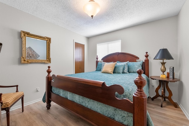 bedroom featuring baseboards, a textured ceiling, and light wood-style floors