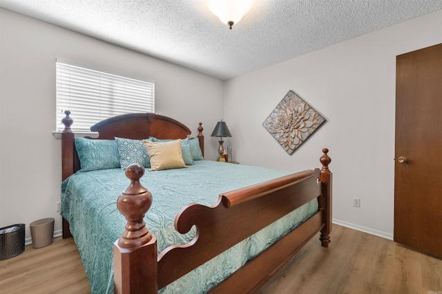 bedroom with wood finished floors, baseboards, and a textured ceiling