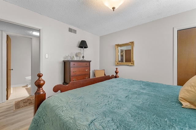 bedroom featuring wood finished floors, visible vents, and a textured ceiling