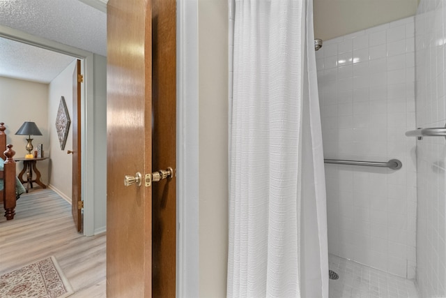 interior space with a shower stall, a textured ceiling, and wood finished floors