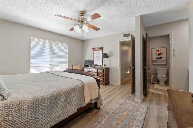 bedroom featuring visible vents, baseboards, ceiling fan, light wood-style floors, and a textured ceiling