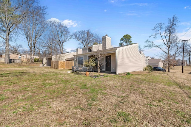 rear view of house with a yard, fence, and a chimney