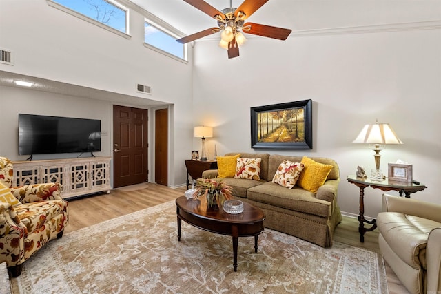 living room featuring wood finished floors, a ceiling fan, visible vents, and baseboards