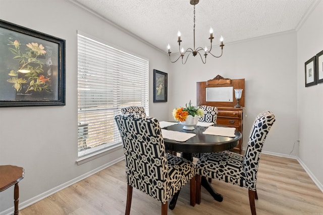 dining area with baseboards, a chandelier, ornamental molding, light wood-style floors, and a textured ceiling