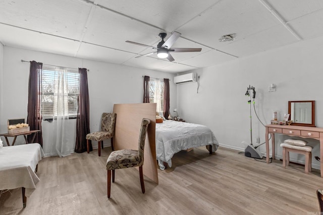 bedroom with a wall mounted air conditioner, baseboards, light wood-style floors, and ceiling fan