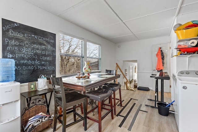 dining space with a paneled ceiling, light wood-style floors, and washer / dryer