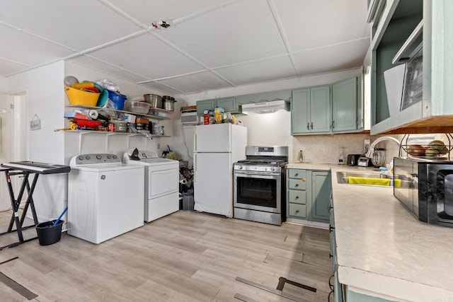 kitchen with stainless steel gas range oven, green cabinets, a sink, and freestanding refrigerator