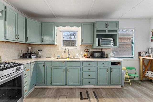 kitchen featuring light countertops, light wood-style floors, stainless steel gas stove, and a sink