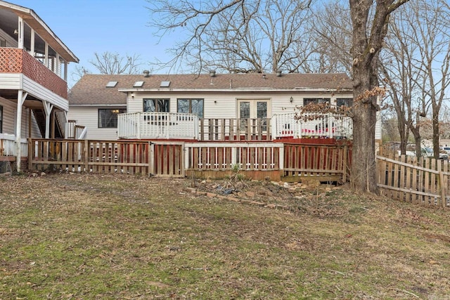 back of property with a shingled roof, a yard, fence, and a wooden deck