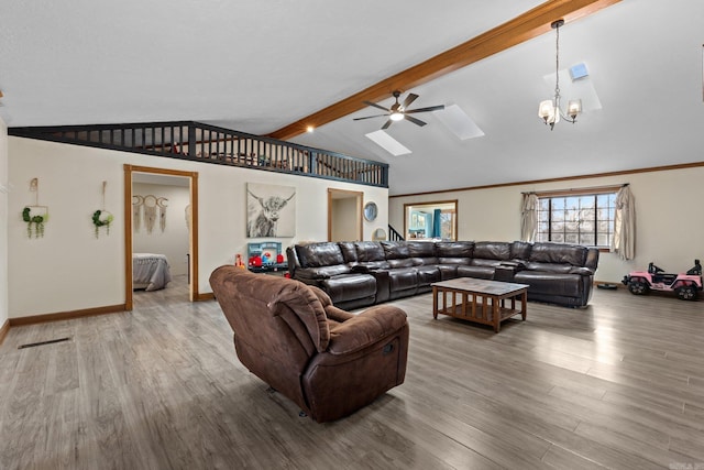 living area with visible vents, baseboards, vaulted ceiling with skylight, ceiling fan with notable chandelier, and wood finished floors