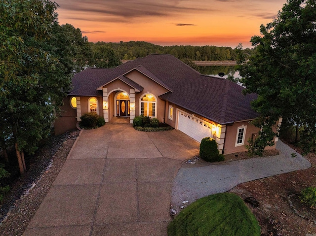 view of front facade with a garage, concrete driveway, stucco siding, and a shingled roof