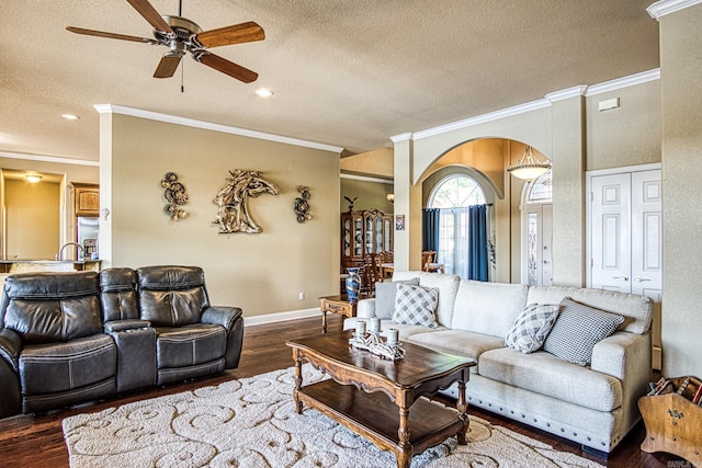 living area with a textured ceiling, crown molding, wood finished floors, and ceiling fan