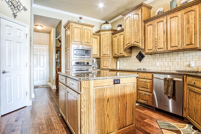 kitchen with ornamental molding, dark wood-style floors, a center island, appliances with stainless steel finishes, and stone counters