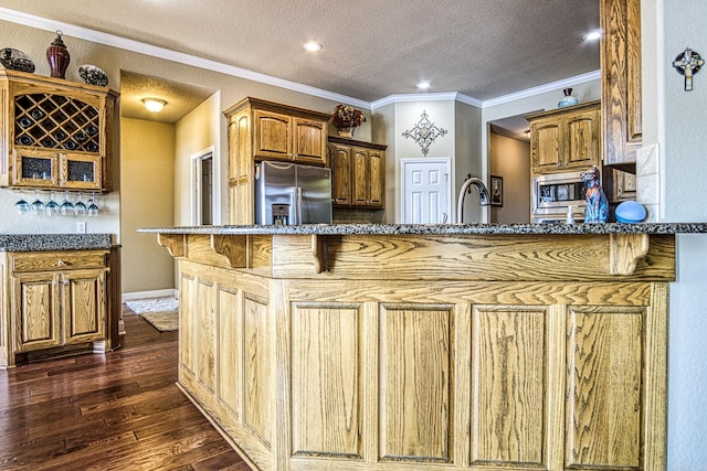 kitchen featuring dark wood-type flooring, crown molding, dark stone counters, stainless steel appliances, and a textured ceiling