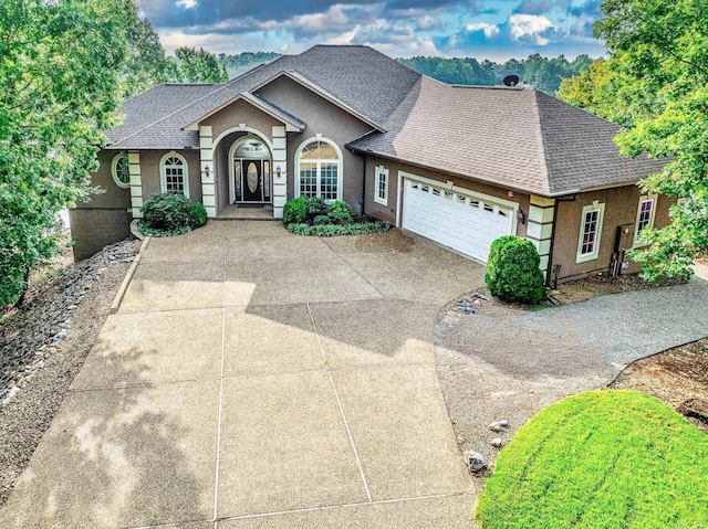 view of front of home with stucco siding, concrete driveway, an attached garage, and a shingled roof