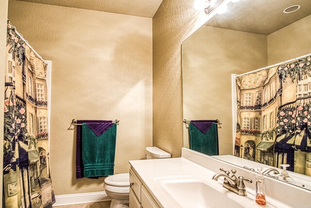 full bath with curtained shower, toilet, vanity, and a textured wall