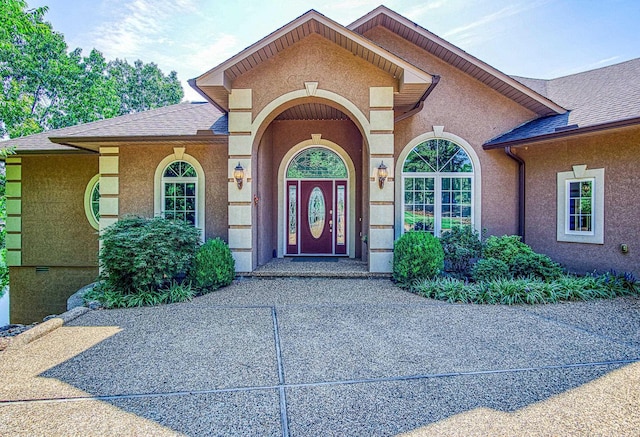 doorway to property with a shingled roof and stucco siding