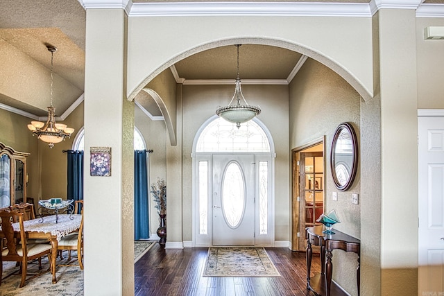 entryway with baseboards, an inviting chandelier, arched walkways, hardwood / wood-style flooring, and crown molding