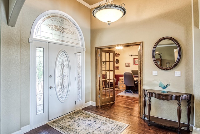 entrance foyer featuring dark wood-type flooring, a high ceiling, and crown molding