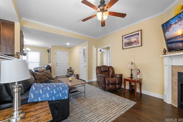 living area with crown molding, wood finished floors, a ceiling fan, and a tile fireplace