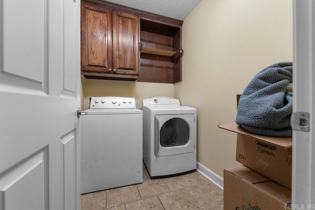 washroom featuring cabinet space, washer and dryer, a textured ceiling, and baseboards