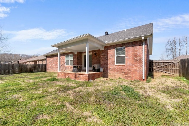 back of property featuring a yard, a patio area, brick siding, and a fenced backyard