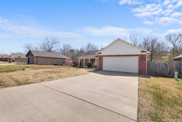 view of front of house with brick siding, fence, concrete driveway, a front yard, and a garage