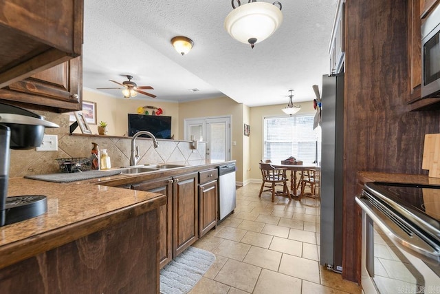 kitchen featuring decorative backsplash, appliances with stainless steel finishes, a textured ceiling, a ceiling fan, and a sink