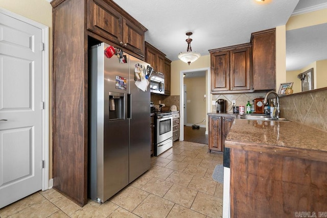 kitchen with decorative backsplash, pendant lighting, appliances with stainless steel finishes, and a sink