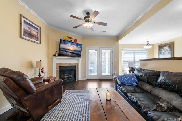 living room featuring visible vents, crown molding, ceiling fan, a fireplace, and wood finished floors