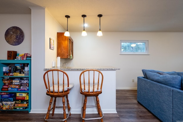 kitchen featuring crown molding, a peninsula, dark wood-type flooring, and a kitchen breakfast bar