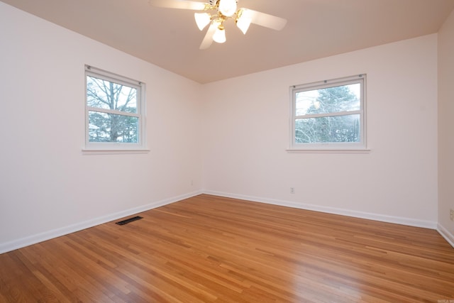 unfurnished room featuring a wealth of natural light, visible vents, light wood-style flooring, and baseboards