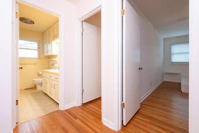 hall featuring tile walls and light wood-style flooring