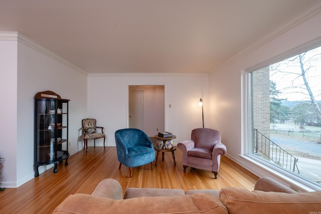 sitting room with baseboards, crown molding, and light wood-style floors