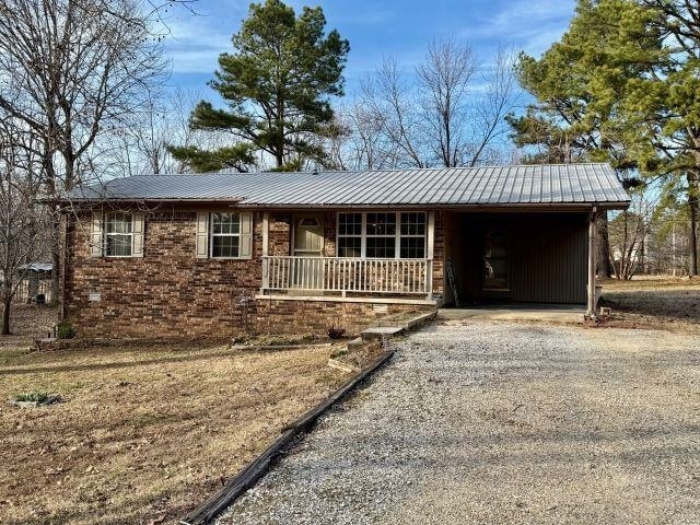 ranch-style house featuring a carport, a porch, driveway, and metal roof