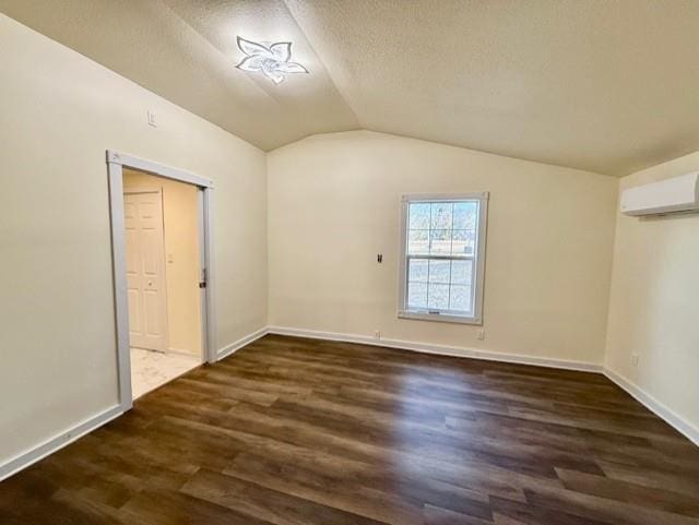 bonus room with wood finished floors, baseboards, an AC wall unit, vaulted ceiling, and a textured ceiling