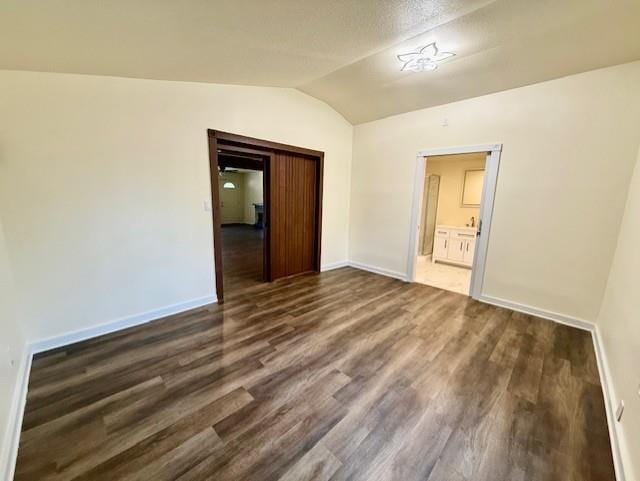 unfurnished room featuring wood finished floors, baseboards, and vaulted ceiling