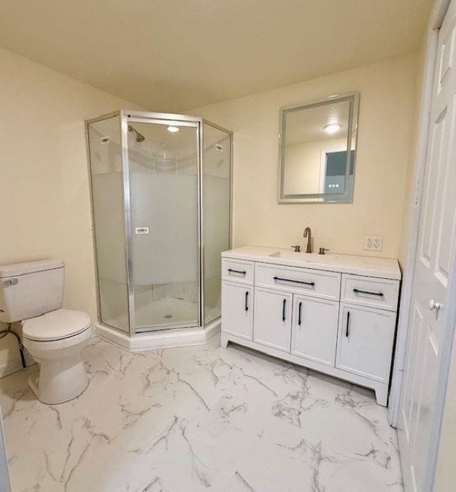 bathroom with a shower stall, vanity, toilet, and marble finish floor