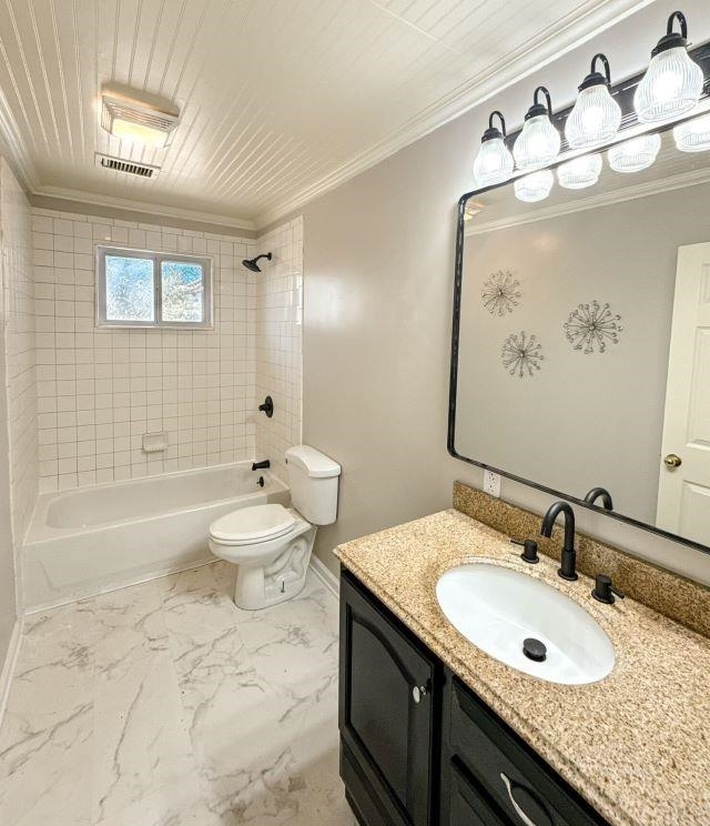 full bath featuring bathing tub / shower combination, toilet, marble finish floor, and crown molding